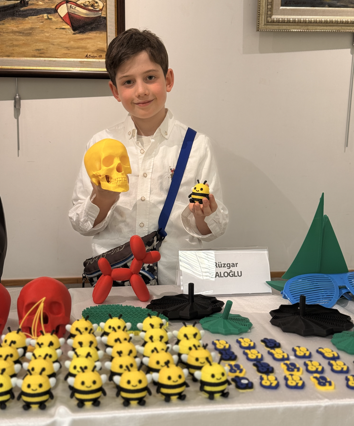 Rüzgar Zaloğlu at his maker stand with 3D-printed skulls, bees and figures